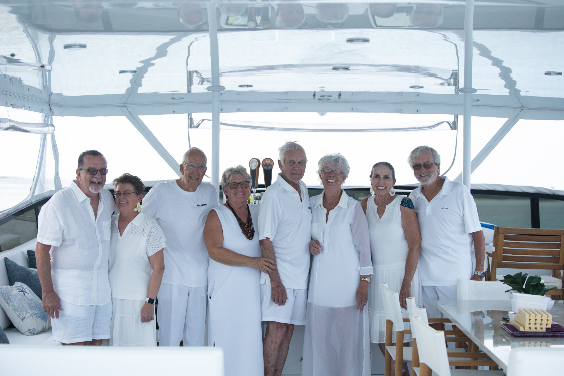 Group portrait in white attire under the sundeck awning