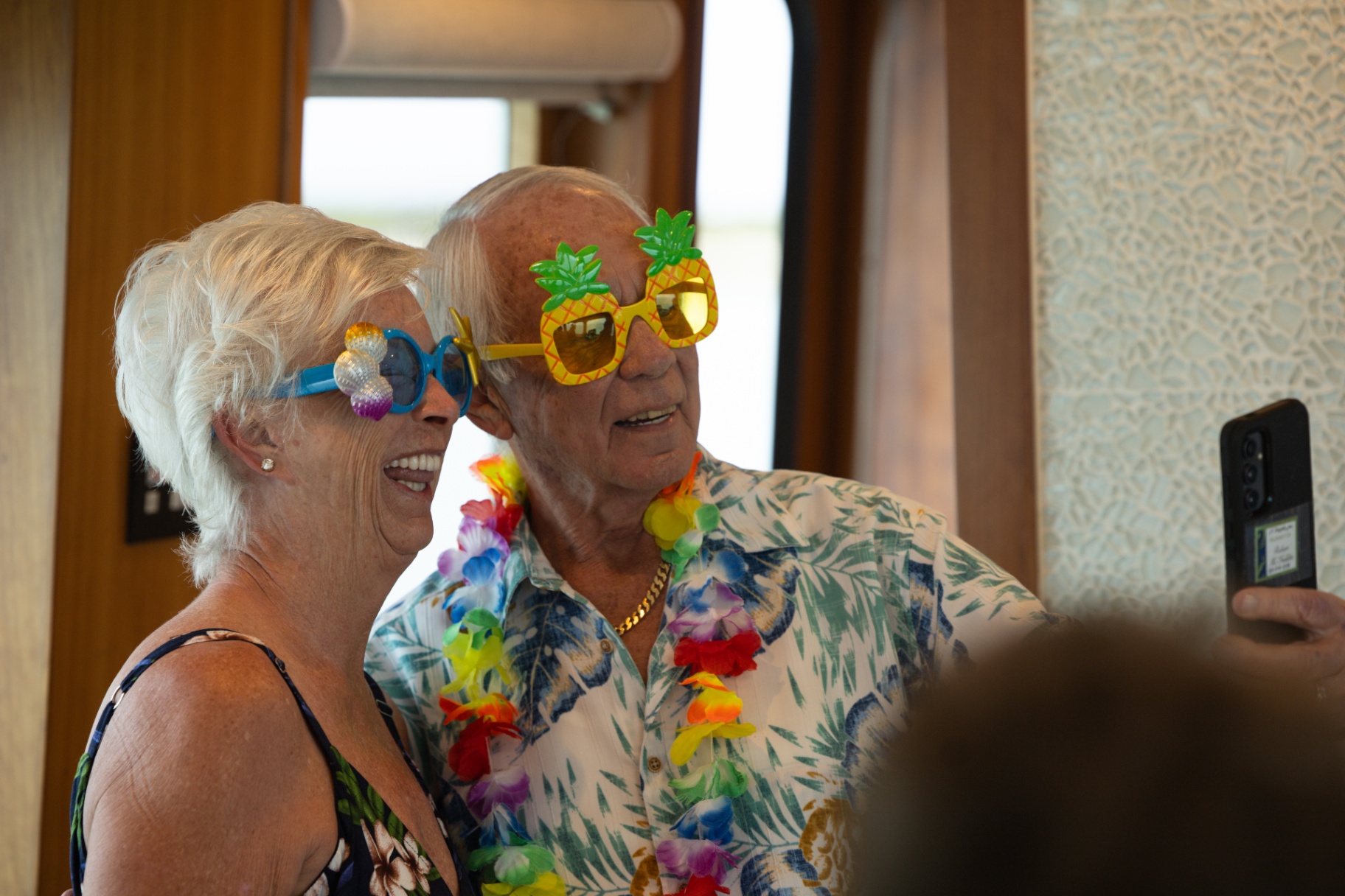 Guests laughing in pineapple sunglasses and leis